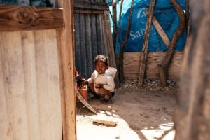 A child squatting in a hut.