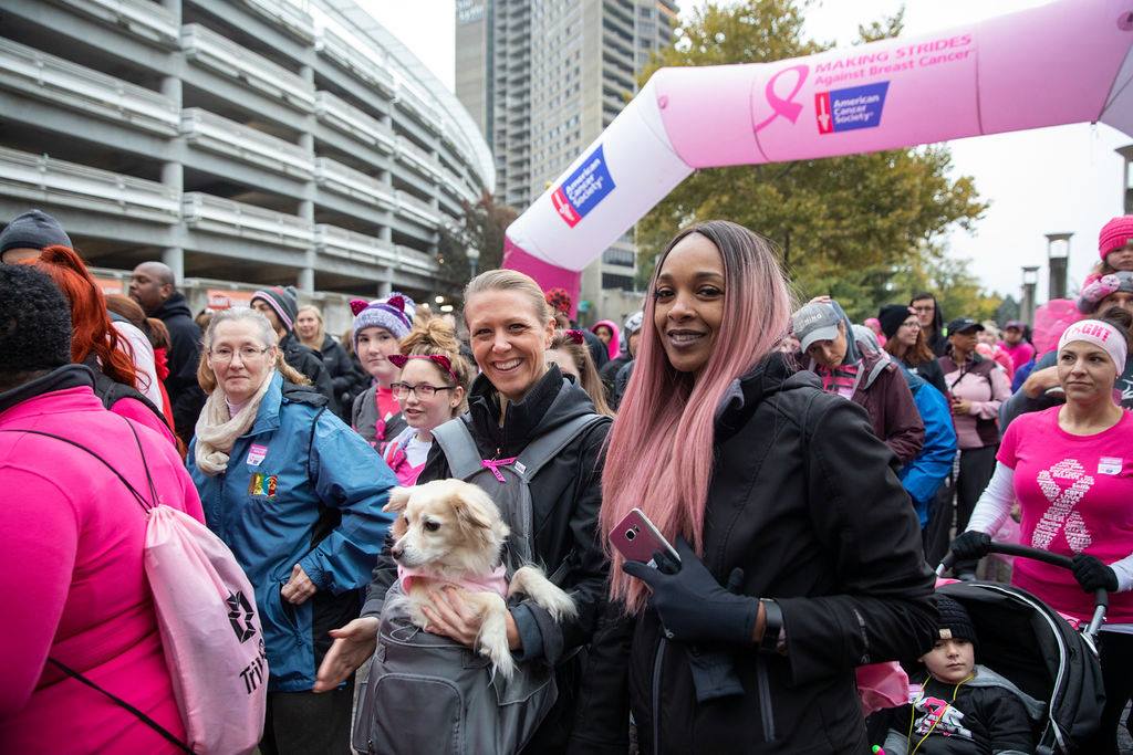 A group of women and a dog at a pink event.