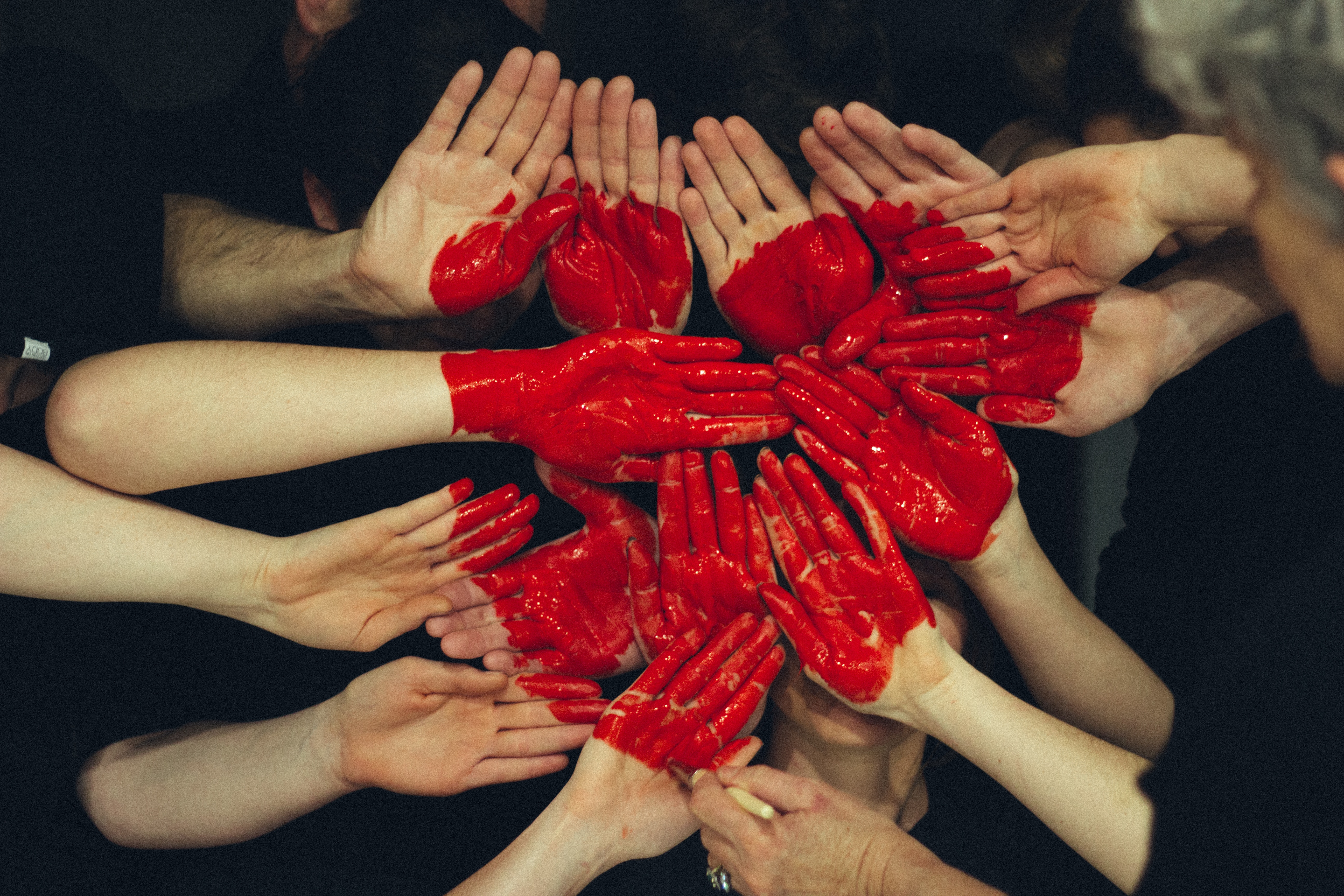 A group of people with red painted hands in a circle.
