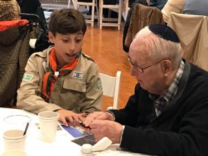 A scout helping a boy at a table.