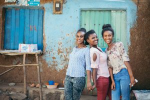 Three young women standing in front of a house in ethiopia.