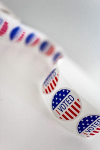 A roll of voting stickers on a white surface.